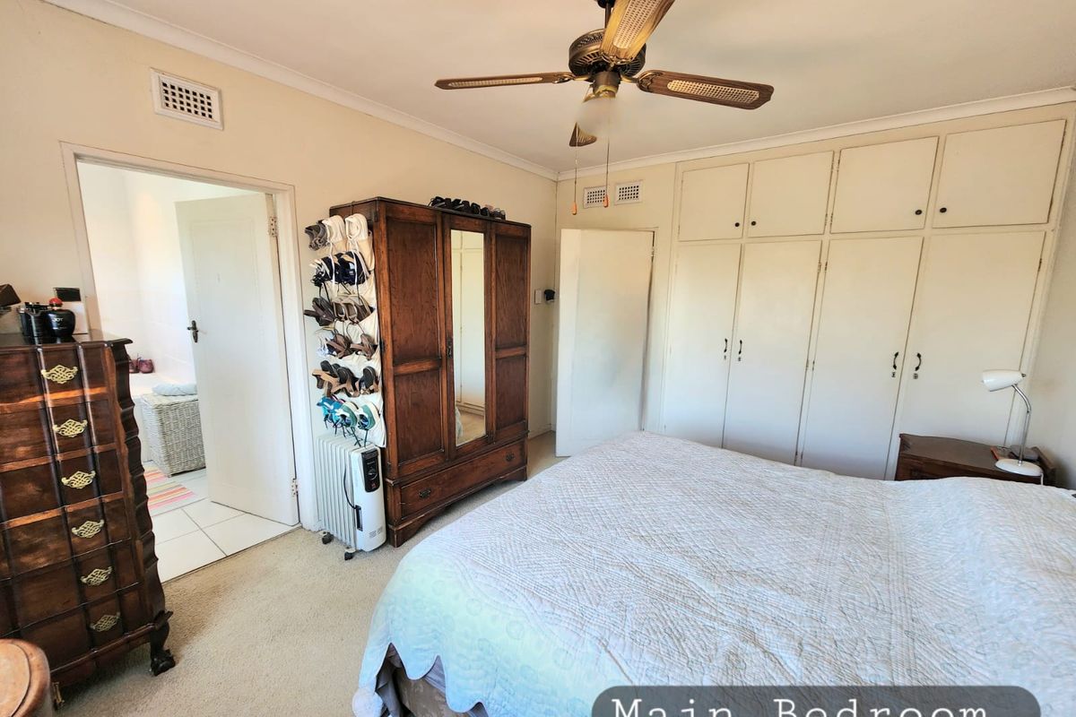 Main bedroom featuring built-in floor-to-ceiling wardrobes, a ceiling fan, and direct access to an adjoining bathroom.