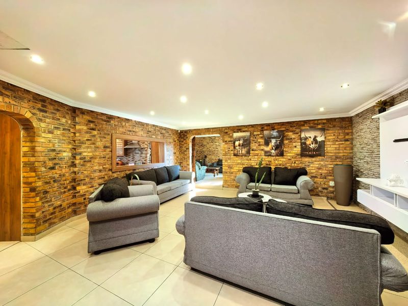 Spacious living room featuring exposed brick walls, recessed downlighting, and neutral tiled flooring, creating a warm and textured interior space.