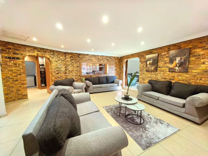 Spacious living room featuring distinctive exposed brick walls, arched architectural transitions, and modern recessed lighting throughout the open-plan area.