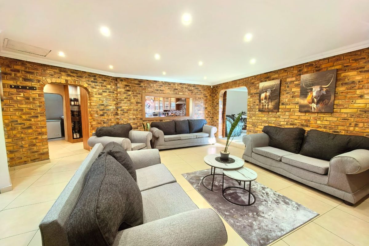 Spacious living room featuring distinctive exposed brick walls, arched architectural transitions, and modern recessed lighting throughout the open-plan area.