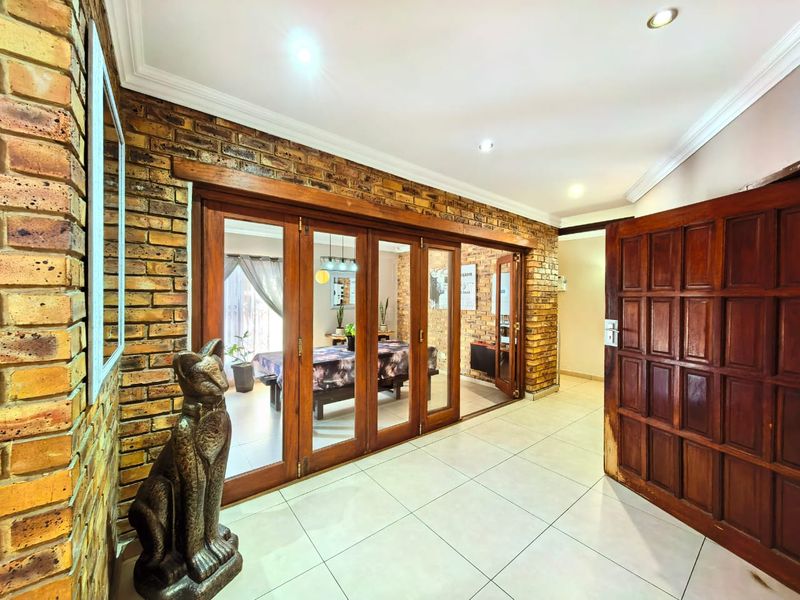 Entrance hall featuring exposed brick walls, tiled flooring, and wooden folding doors leading into the adjacent living space.