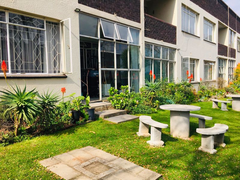 Ground floor flat exterior featuring a private garden area with concrete seating and direct access through large glass windows and doors.
