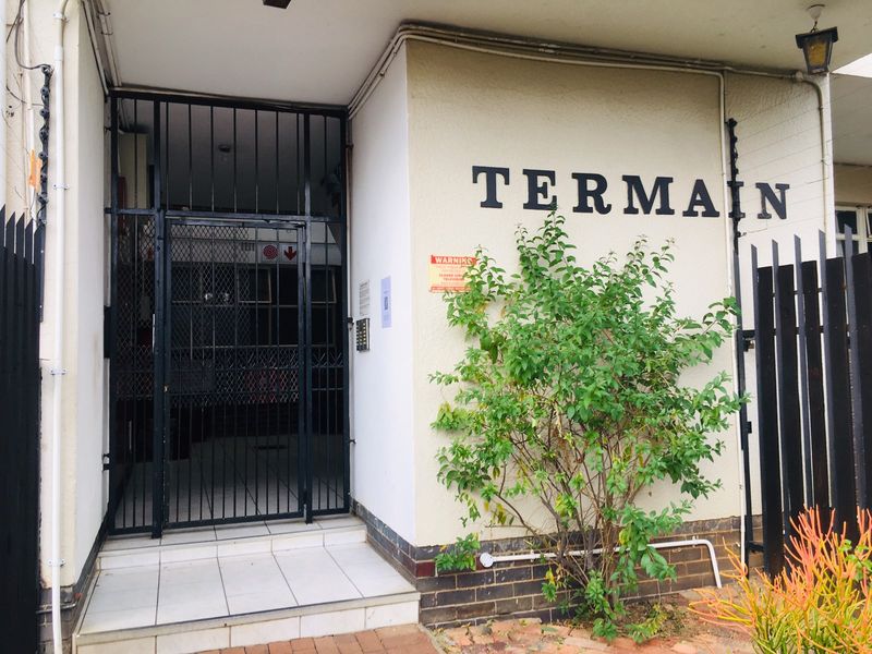 The entrance to the Terrain building features a secure metal gate, tiled step, and intercom system, providing access to the residential complex.