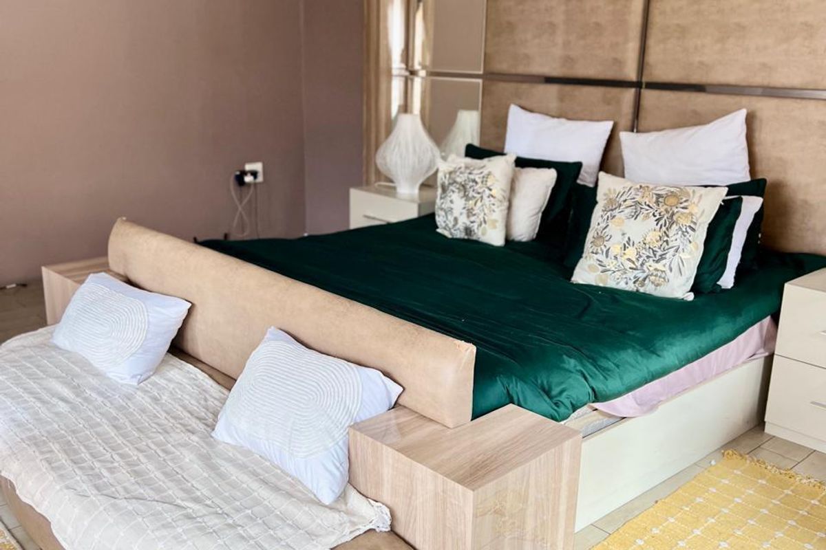 A well-maintained bedroom featuring tiled flooring, a built-in headboard with integrated shelving, and neutral wall finishes.