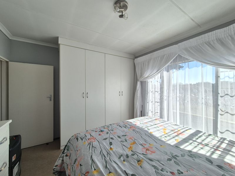 A well-lit bedroom featuring built-in cupboards, neutral wall finishes, and carpeted flooring, offering a comfortable and functional living space.