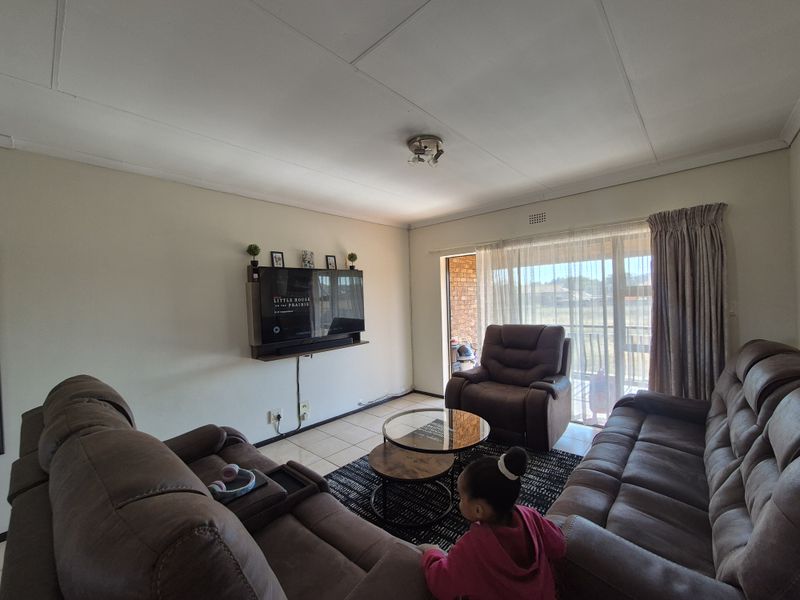 A comfortable living room featuring tiled flooring and a large sliding glass door providing access to the outdoor patio area.