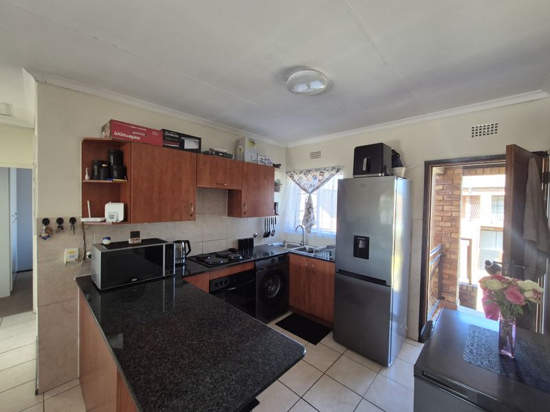 Functional kitchen featuring granite countertops, built-in cabinetry, and a tiled backsplash, with direct access to an exterior area.