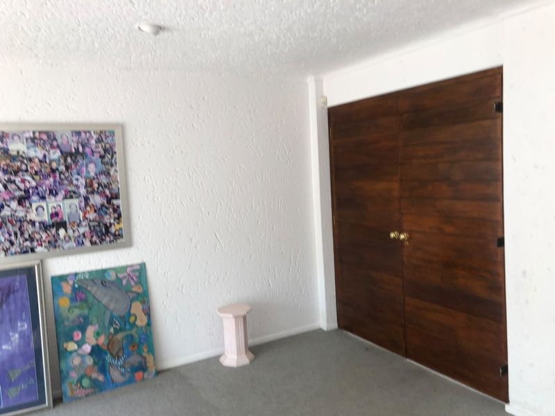 A bedroom featuring textured walls, grey carpeting, and double wooden closet doors.