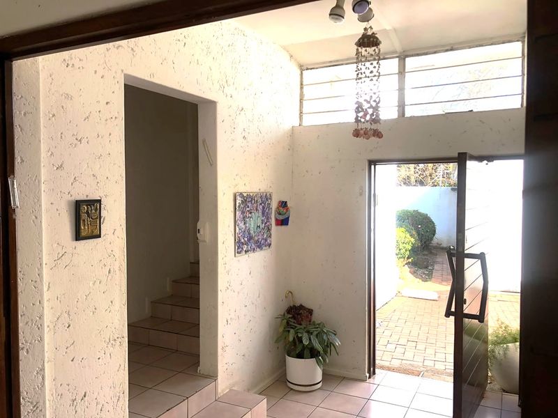 Entrance hall featuring tiled flooring, textured walls, and clerestory windows, providing direct access to the interior staircase and outdoor area.
