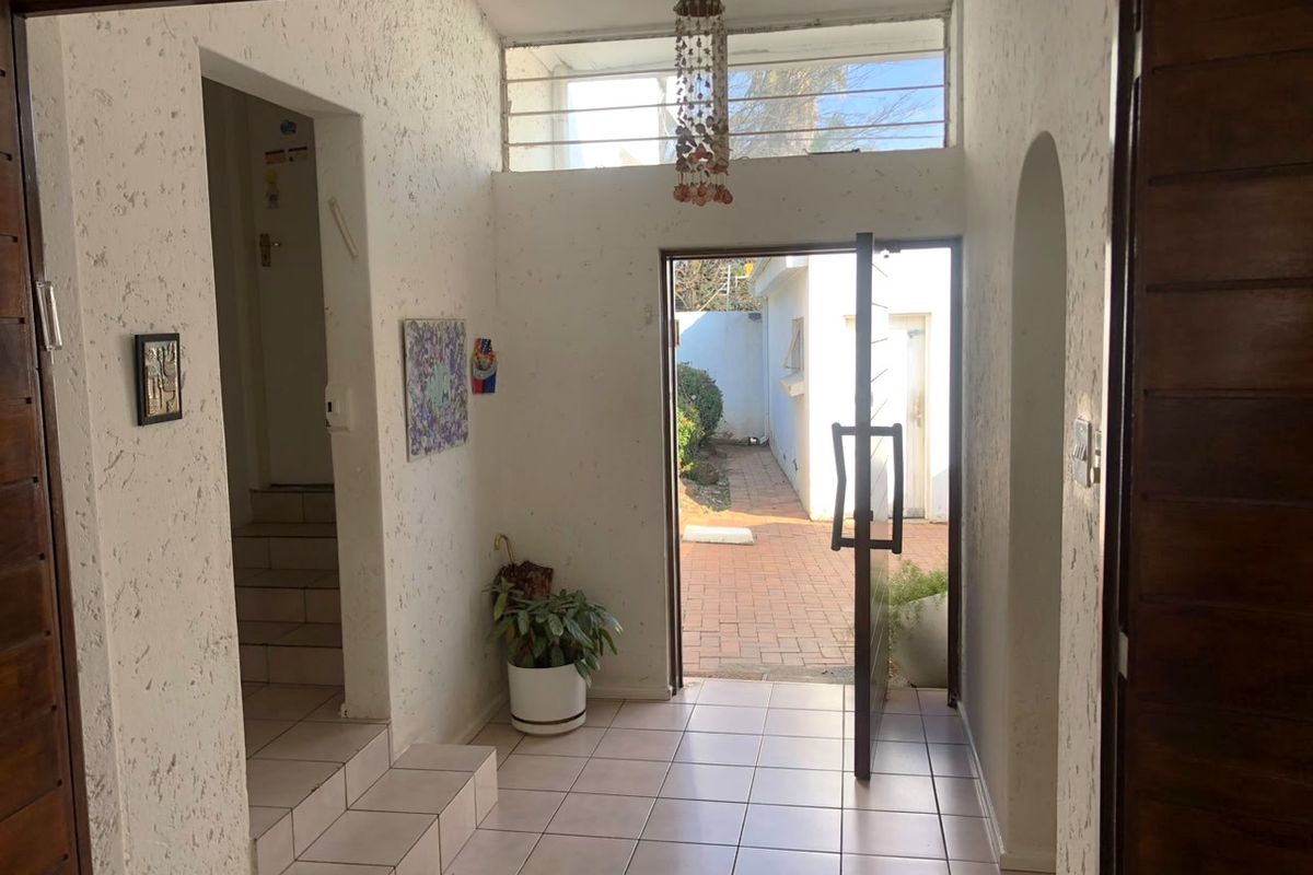 Entrance foyer featuring tiled flooring, textured walls, and a transom window, providing direct access to the exterior courtyard.