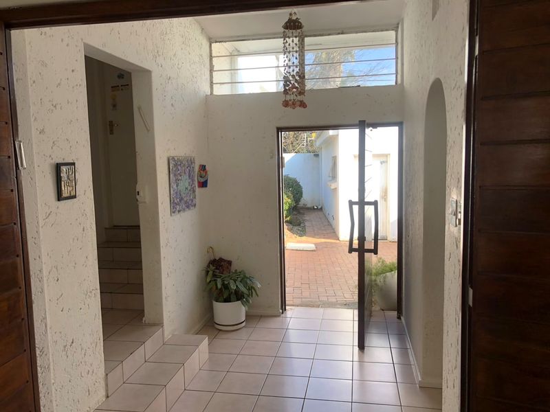 Entrance foyer featuring tiled flooring, textured walls, and a transom window, providing direct access to the exterior courtyard.