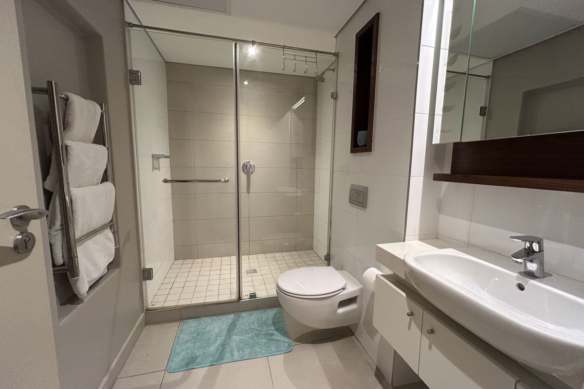 Modern bathroom featuring a glass-enclosed walk-in shower, wall-mounted toilet, and a sleek vanity with integrated basin.