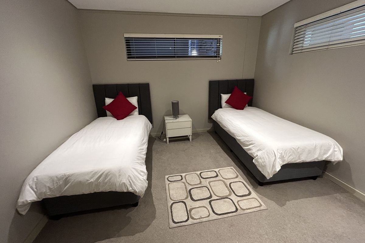 A well-maintained bedroom featuring neutral carpeting, recessed lighting, and two horizontal windows with fitted blinds.