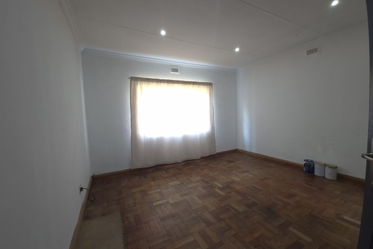 A vacant bedroom featuring classic parquet timber flooring, recessed ceiling downlights, and neutral wall finishes.
