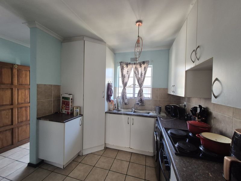 A functional kitchen featuring white cabinetry, laminate countertops, tiled backsplash, and built-in cooking appliances with tiled flooring throughout.
