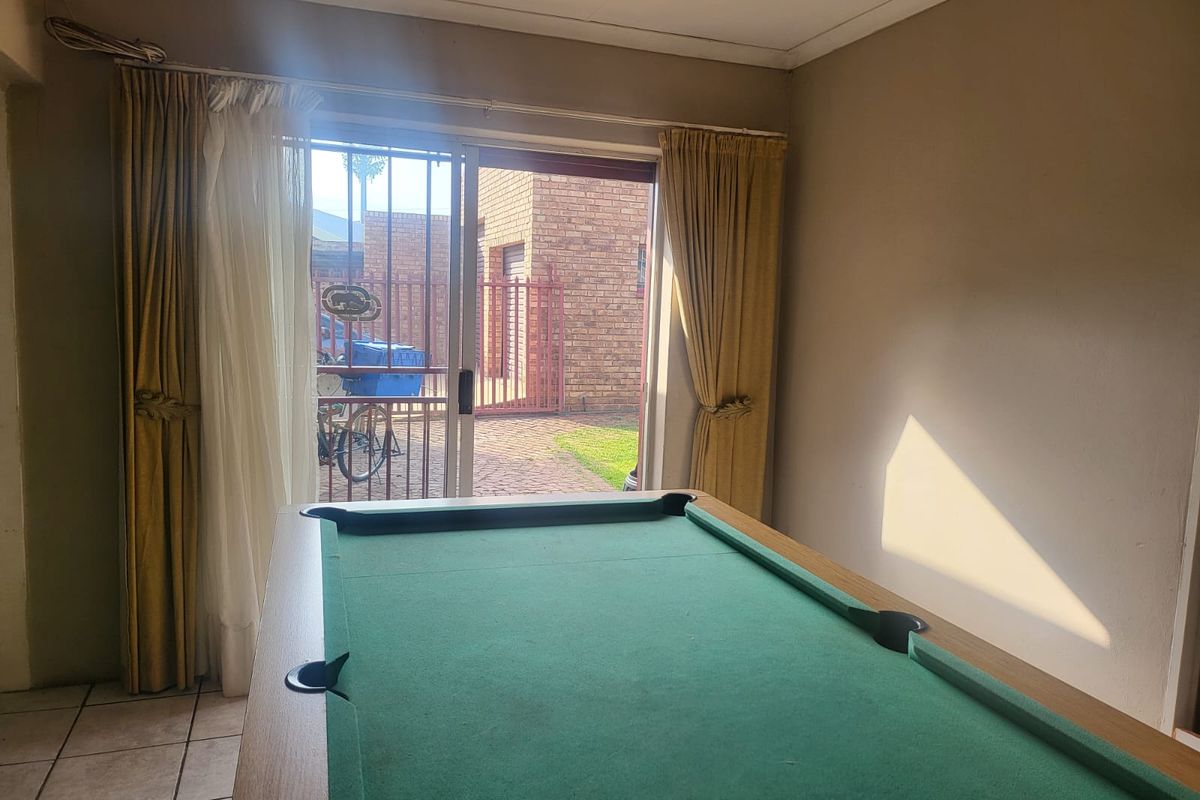 A living area featuring tiled flooring and sliding glass doors that provide direct access to the rear exterior patio and garden area.