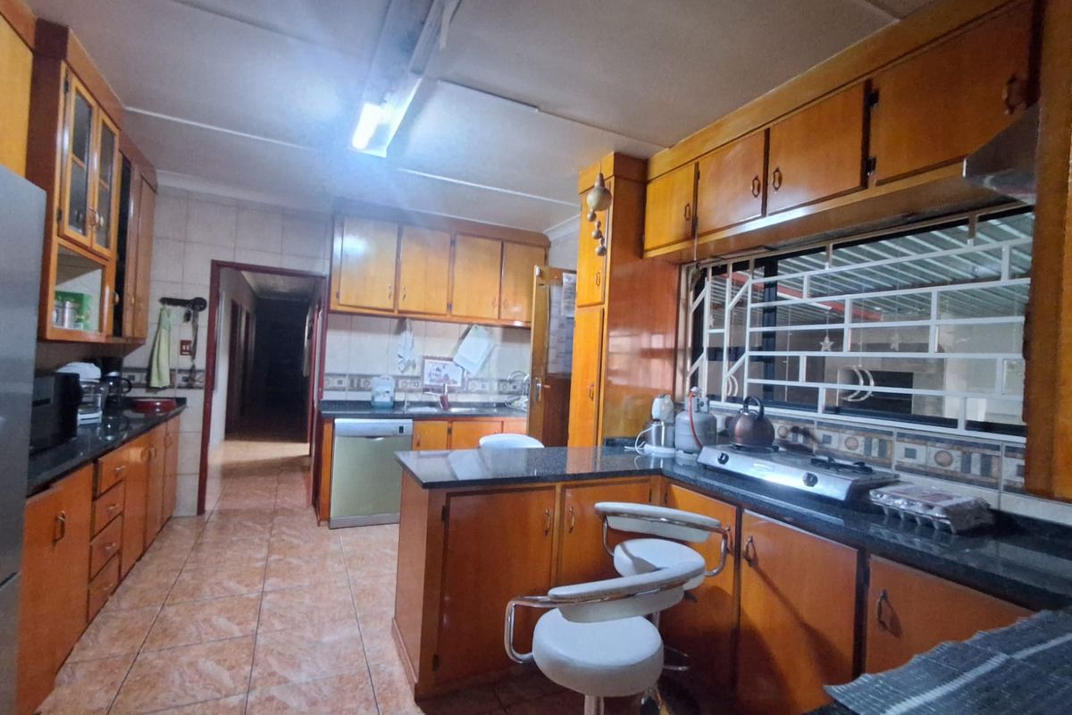 A functional kitchen featuring wooden cabinetry, granite countertops, a breakfast bar, and tiled flooring, offering a traditional layout with ample storage space.