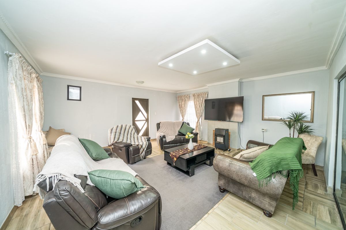 A spacious living room featuring a built-in fireplace, recessed ceiling lighting, and tiled flooring, providing a comfortable and functional family living area.