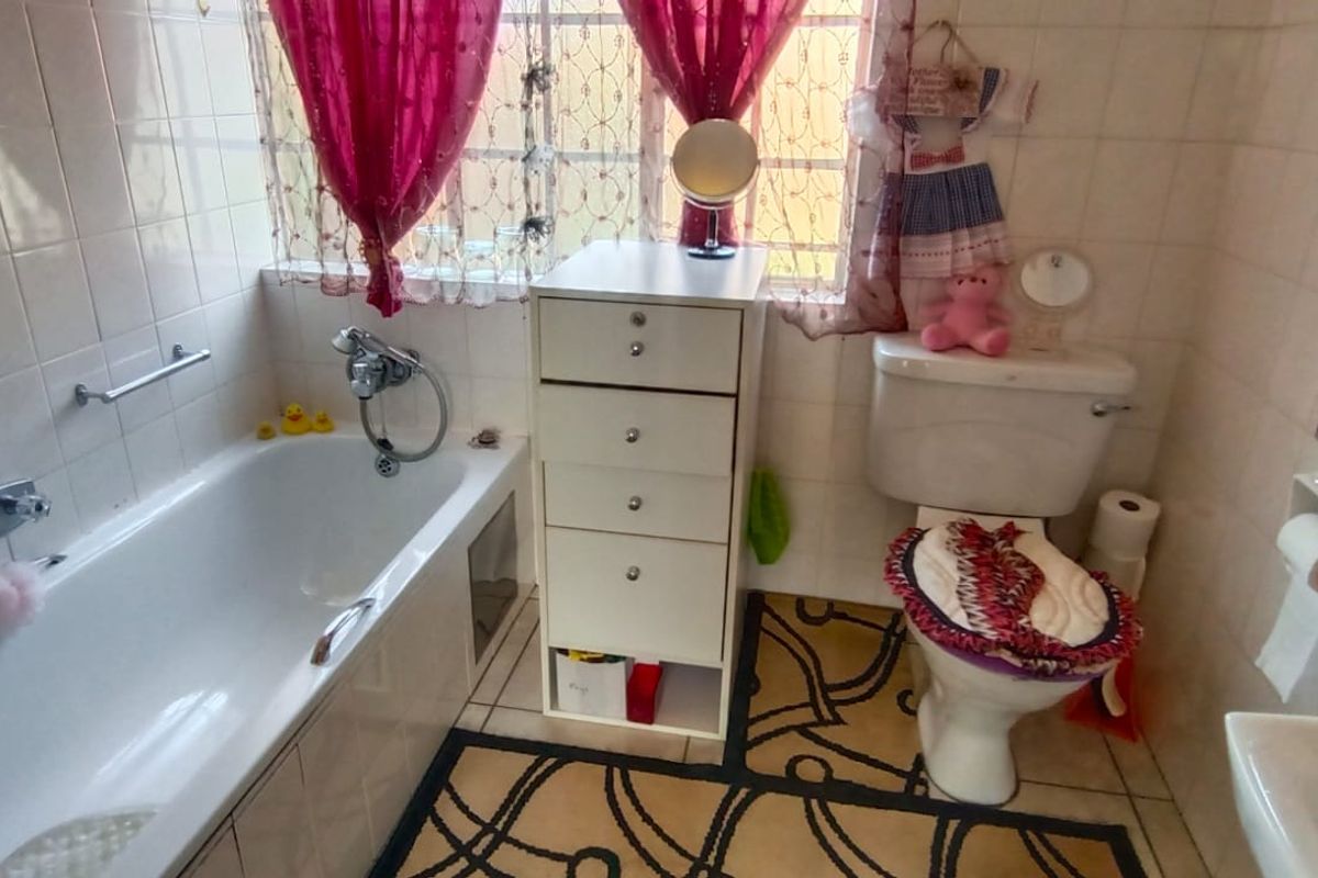 A functional bathroom featuring a standard bathtub with shower mixer, toilet, and basin, finished with full-height wall tiling.