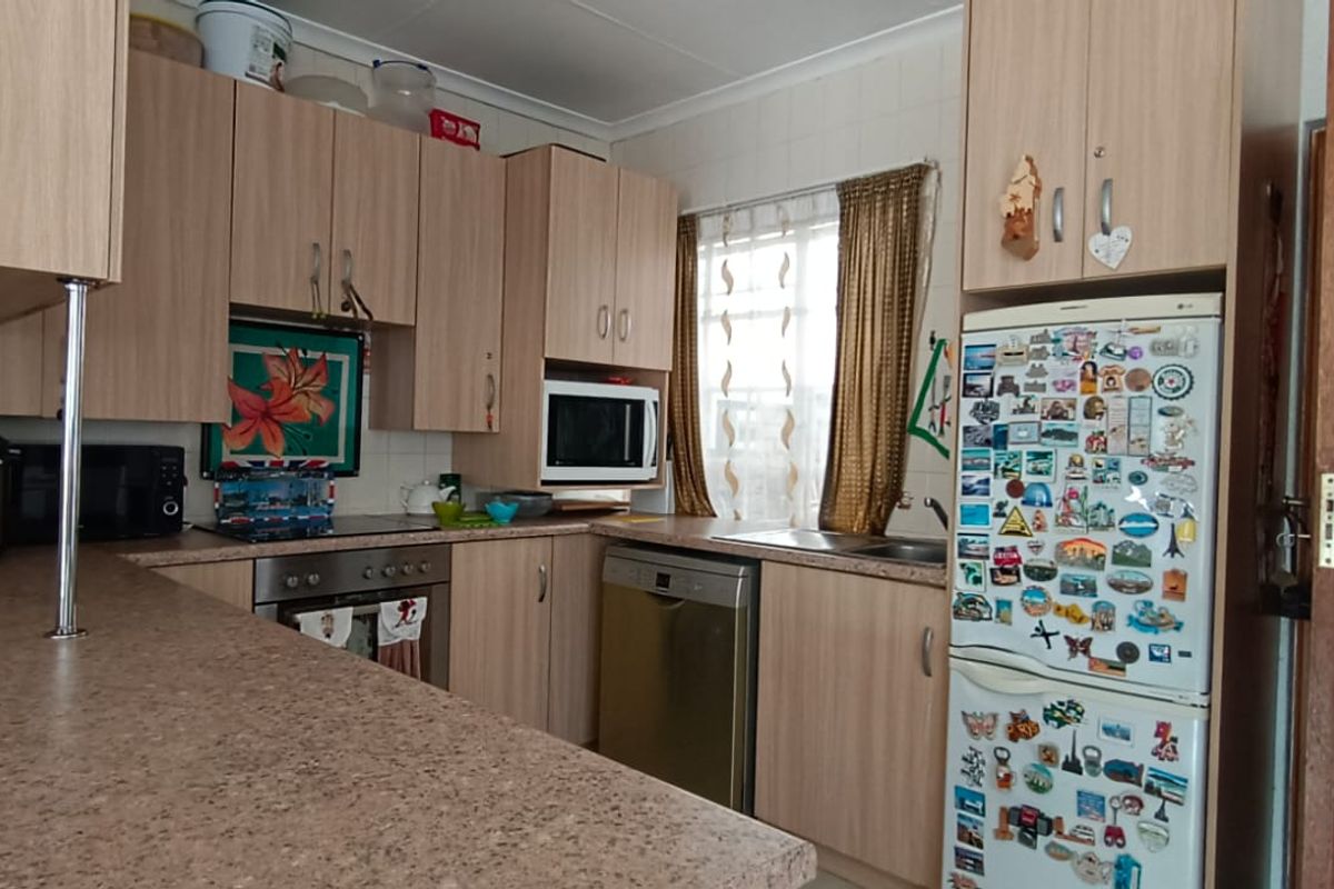 A functional kitchen featuring light wood-finish cabinetry, laminate countertops, a built-in oven, and a stainless steel sink with a window view.