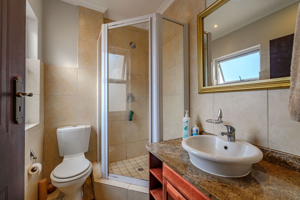 Compact bathroom featuring a corner shower enclosure, a vanity with a granite countertop, a vessel sink, and a toilet.