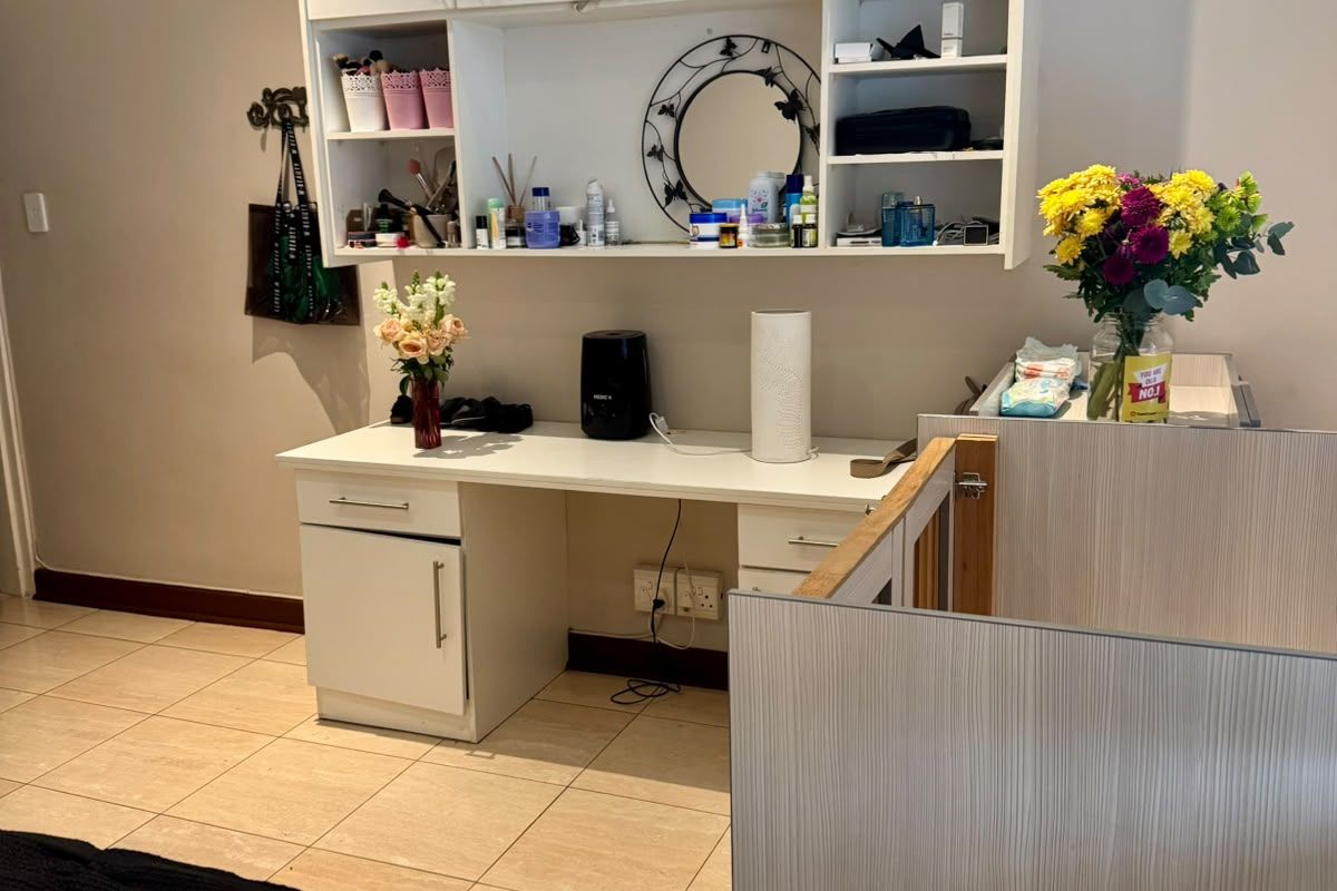A functional bedroom area featuring built-in cabinetry with overhead storage and a dedicated desk workspace with tiled flooring.