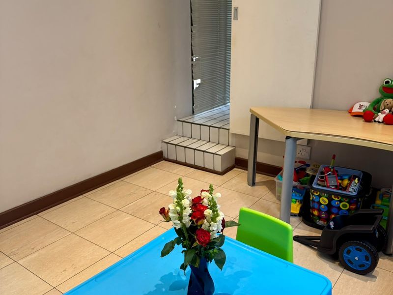 A multi-purpose room featuring tiled flooring and a sliding door leading to an elevated tiled step area.