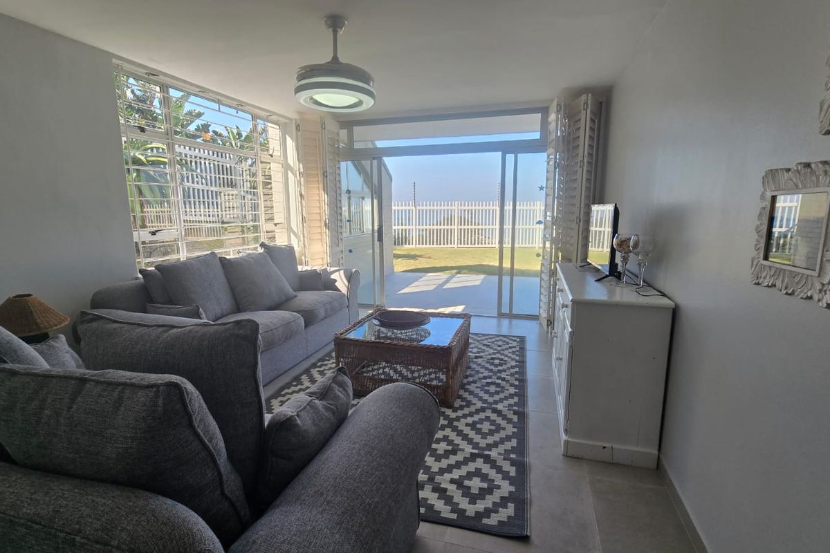 Bright living room featuring large windows and sliding glass doors that open onto a private patio and garden area.