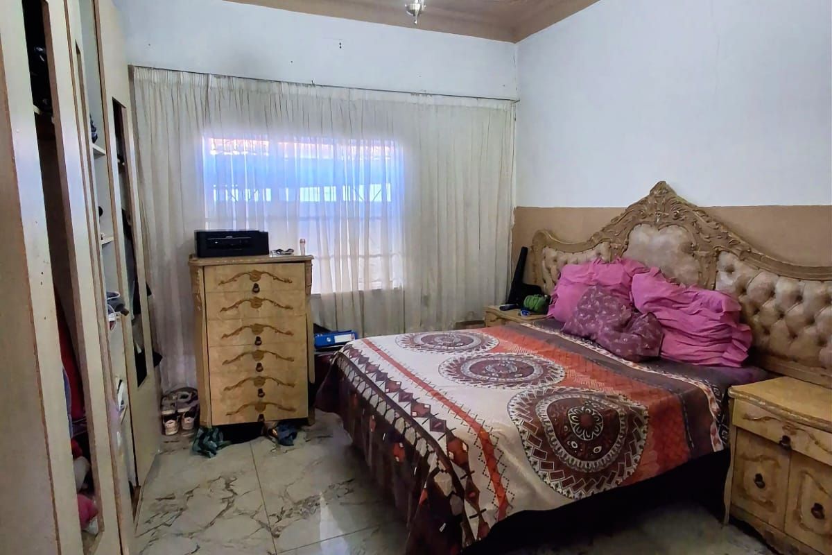 A bedroom featuring tiled flooring, a decorative pressed ceiling with a central light fixture, and built-in wardrobe cabinetry.