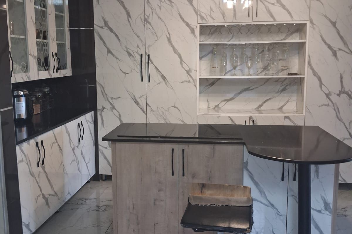 Modern kitchen featuring marble-patterned cabinetry, integrated storage, a central island with a breakfast bar, and polished tiled flooring.