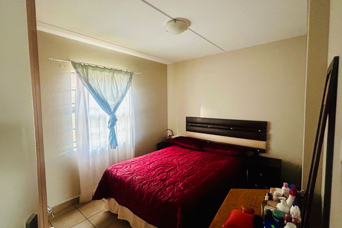 A standard bedroom featuring tiled flooring, a window with curtain rod, and a ceiling-mounted light fixture.