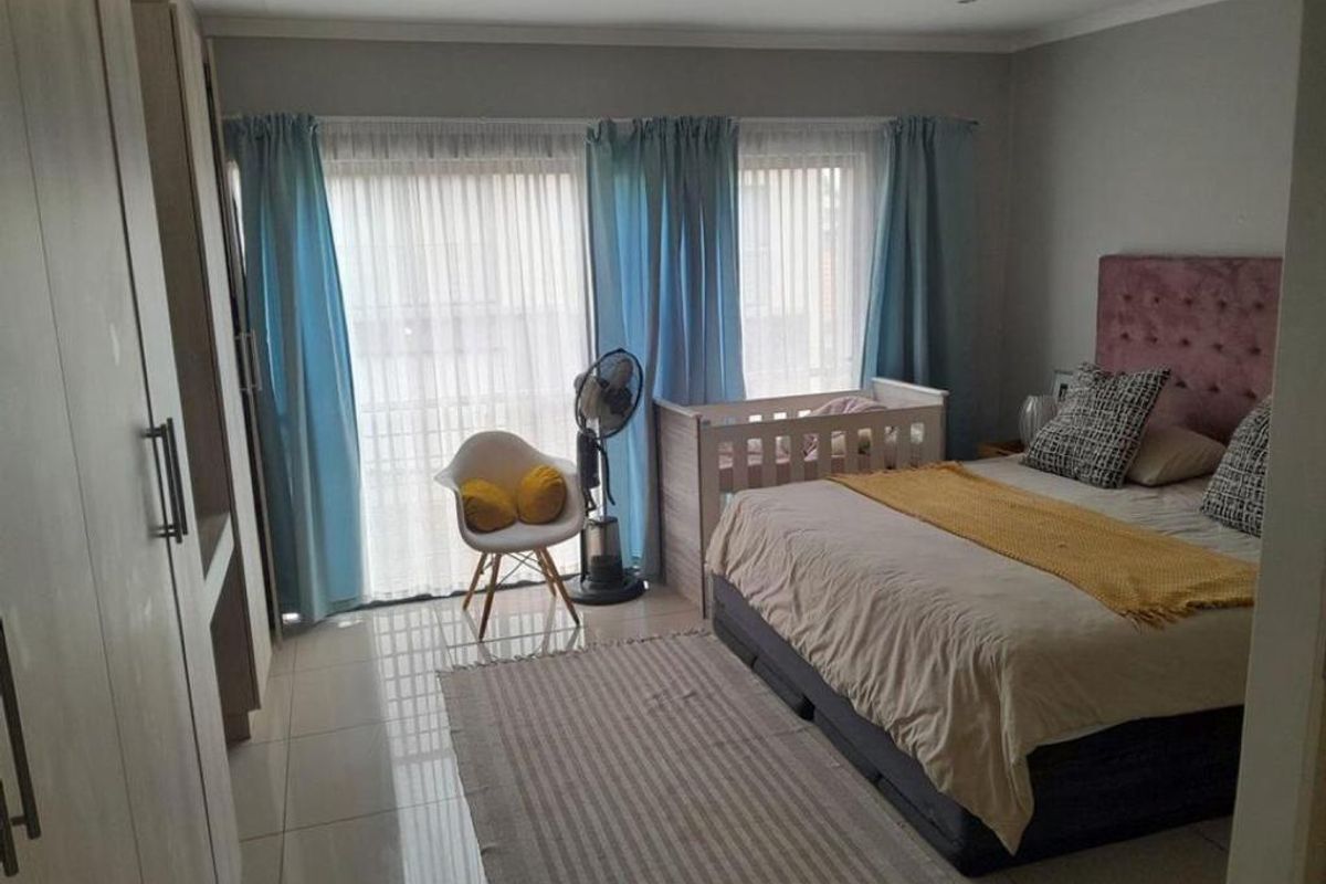 A well-lit bedroom featuring built-in cupboards, tiled flooring, and large sliding glass doors that provide access to an outdoor area.