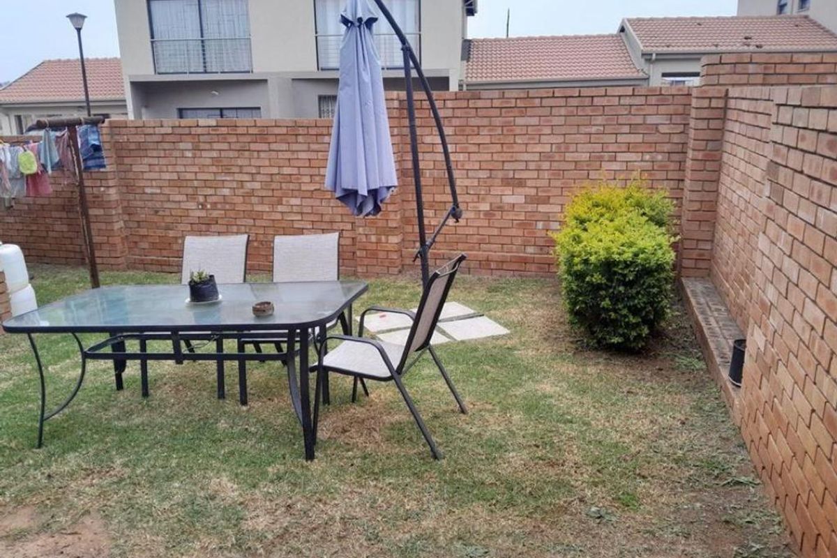 A private rear garden area featuring a brick boundary wall and a small lawn space, suitable for outdoor relaxation.