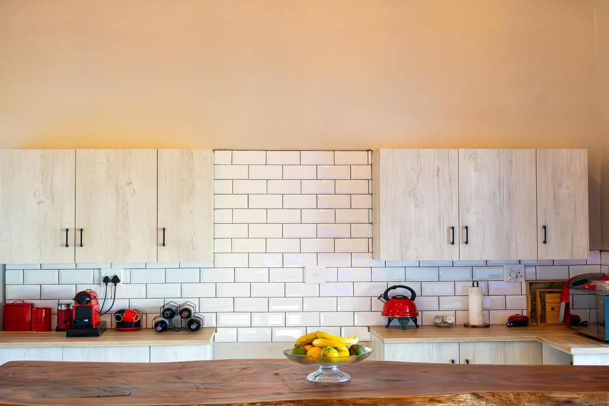 A modern kitchen featuring light wood-grain cabinetry, white subway tile backsplash, and a solid timber countertop.