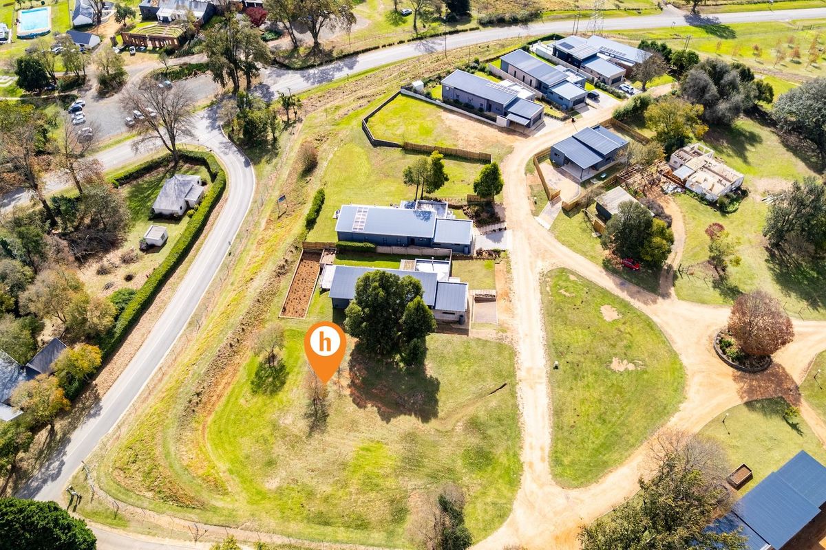 Aerial view of a residential vacant land plot situated within a developed estate, featuring established landscaping and access to local road infrastructure.