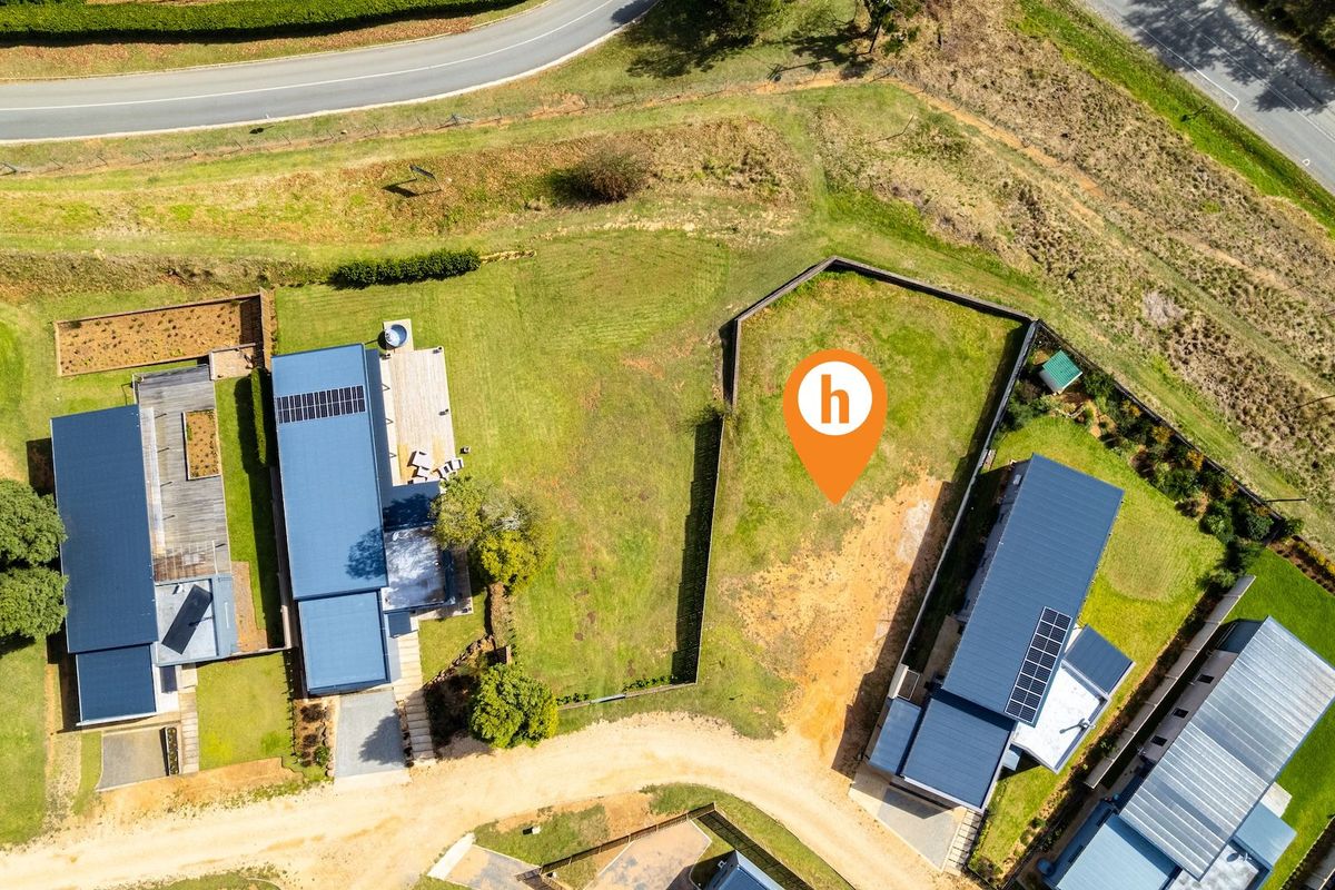 Aerial view of a vacant residential plot situated between existing modern homes, featuring established grass and clear boundaries.