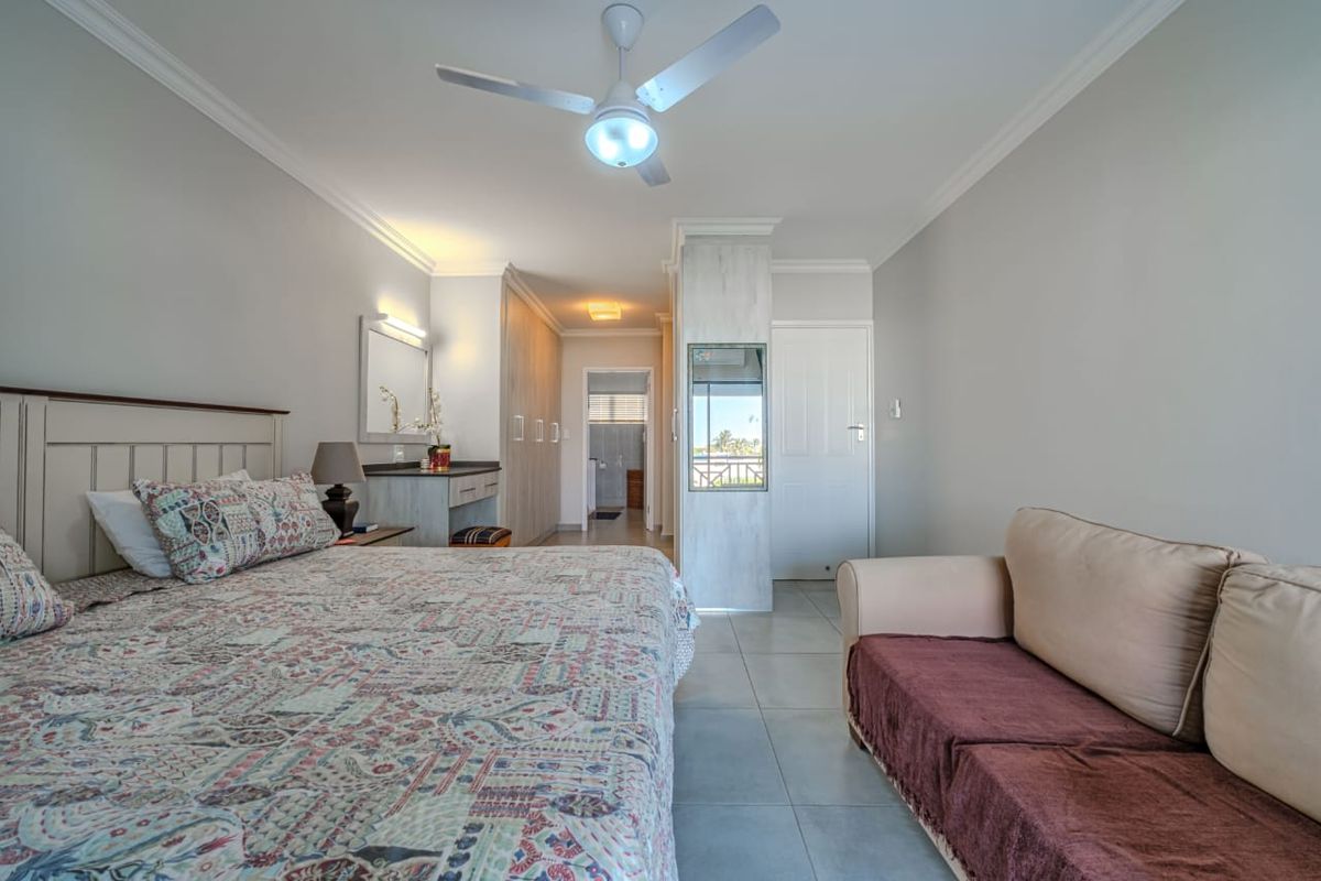 Spacious bedroom featuring built-in cabinetry, a ceiling fan, tiled flooring, and an integrated vanity area with direct access to an en-suite bathroom.