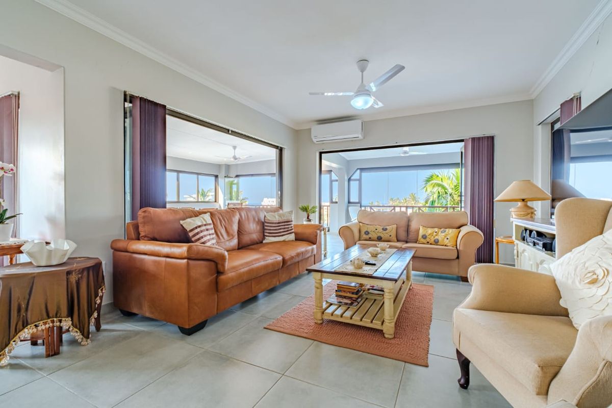 Spacious living area featuring large sliding doors that open onto a covered balcony, complete with a ceiling fan and wall-mounted air conditioning unit.