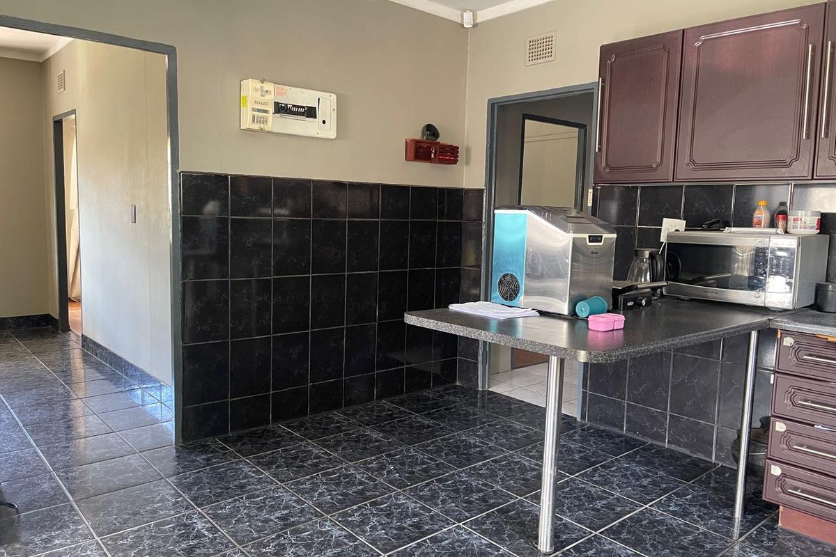 A functional kitchen area featuring dark tiled flooring, matching wall splashbacks, and built-in cabinetry with a breakfast bar counter.