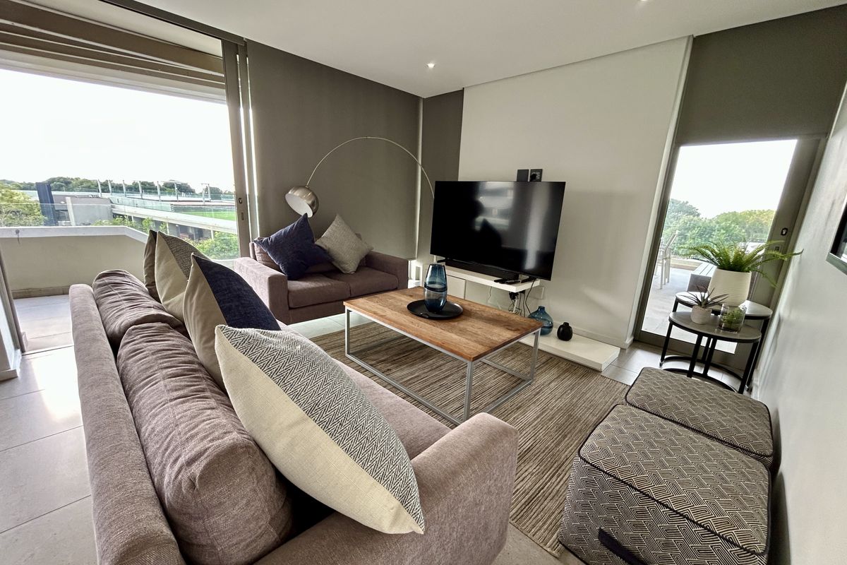 Modern living room featuring tiled flooring, recessed lighting, and large sliding glass doors providing access to an outdoor balcony area.