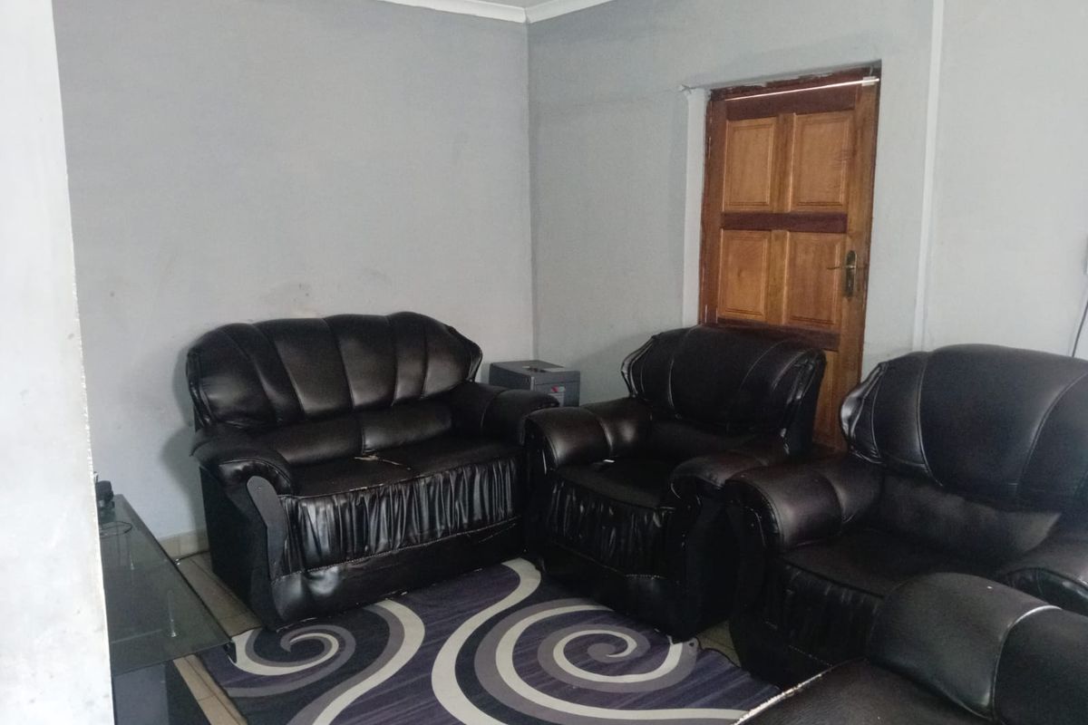 A living room area featuring grey painted walls and a traditional wooden door, providing a functional space for relaxation.