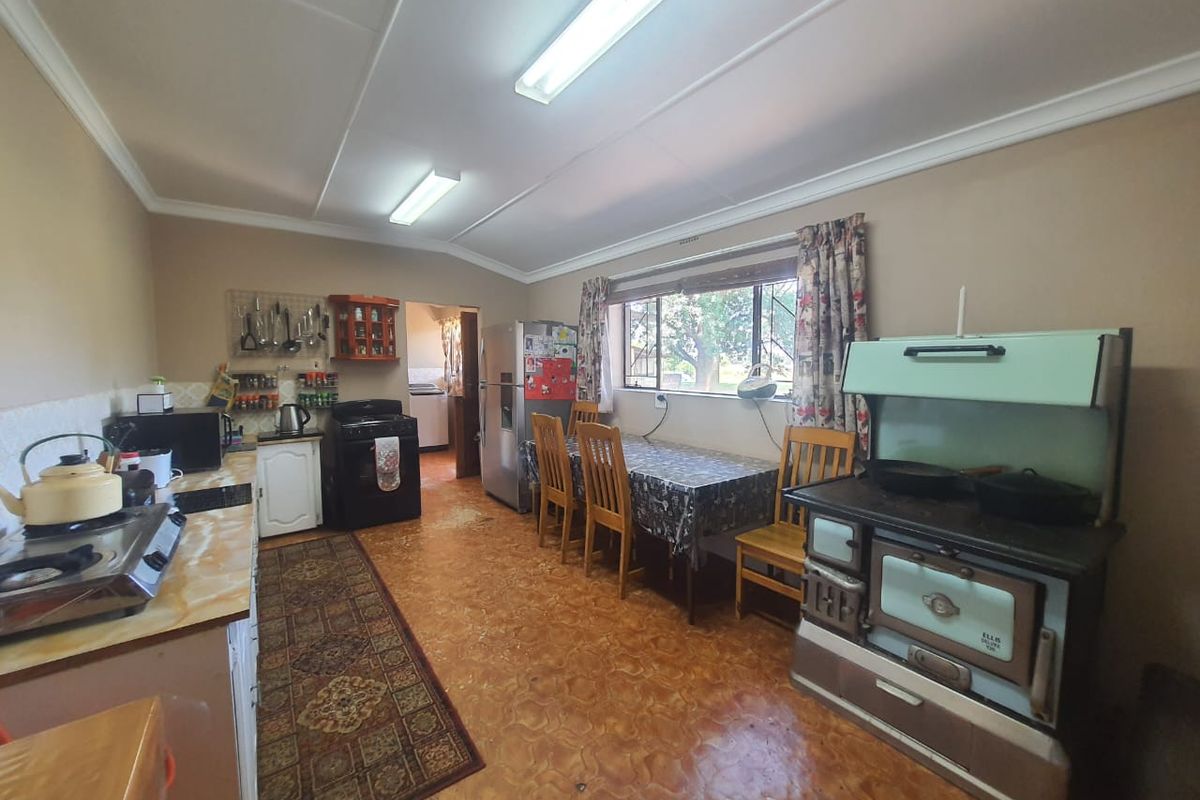 A dated kitchen featuring a vintage stove, laminate countertops, and vinyl flooring, with an adjacent scullery area visible through the doorway.