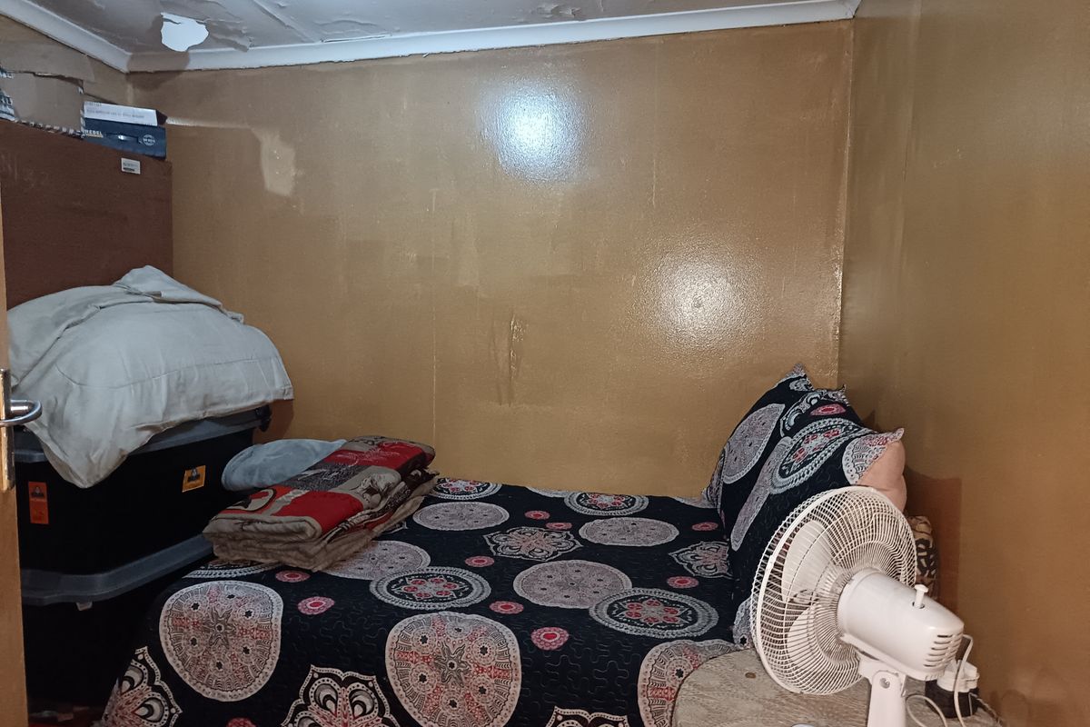A compact bedroom featuring painted walls and a ceiling showing signs of significant wear and plaster damage.