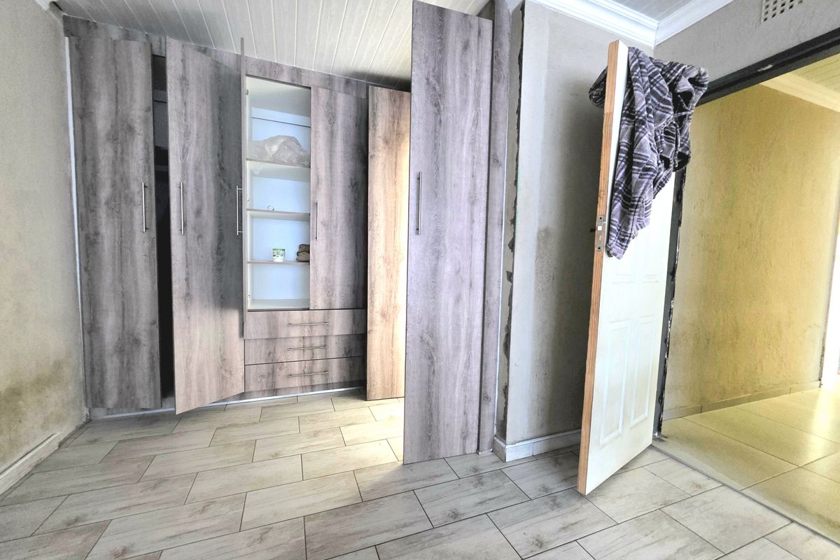 Bedroom featuring built-in wood-look cabinetry, tiled flooring, and tongue-and-groove ceiling, currently requiring finishing touches to walls and door frames.