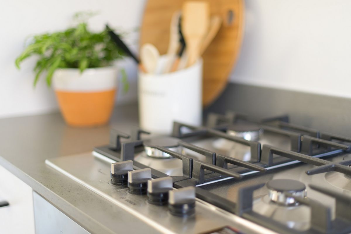 Close-up view of a modern stainless steel gas cooktop set into a stone kitchen benchtop.