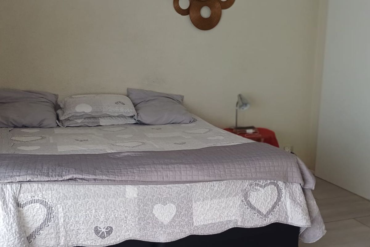 A bedroom featuring light-toned tiled flooring and built-in cupboard storage.