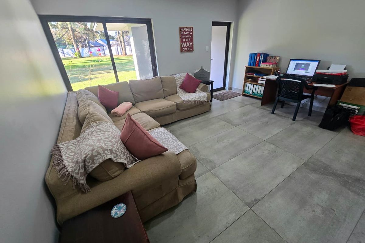 Spacious living area featuring large format floor tiles, sliding glass doors providing garden access, and neutral wall finishes.