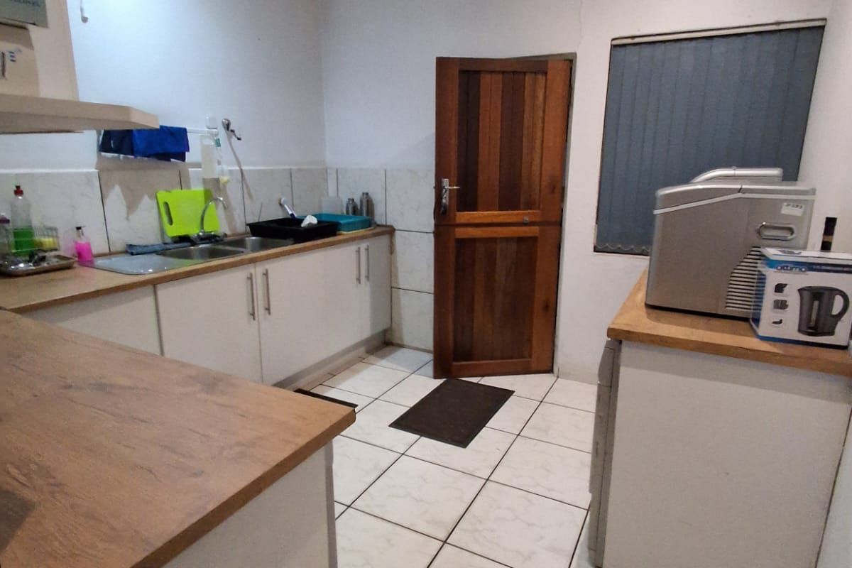 A functional kitchen featuring white cabinetry, wood-look countertops, tiled flooring, and a wooden door leading to an exterior area.
