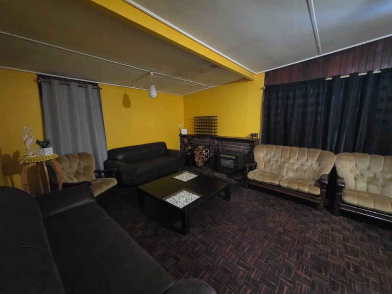 A living room featuring a brick fireplace, wood-look flooring, and yellow walls, offering a dated aesthetic ready for modernization.