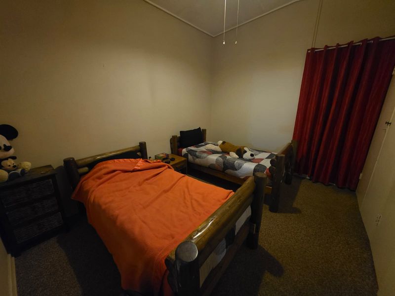 A functional bedroom featuring carpeted flooring and a ceiling fan, providing a comfortable space for rest.